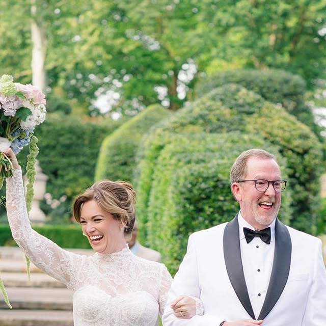 Joyful couple walking up the aisle, bouquet raised in celebration