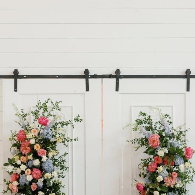 Colorful floral installations flanking white barn doors