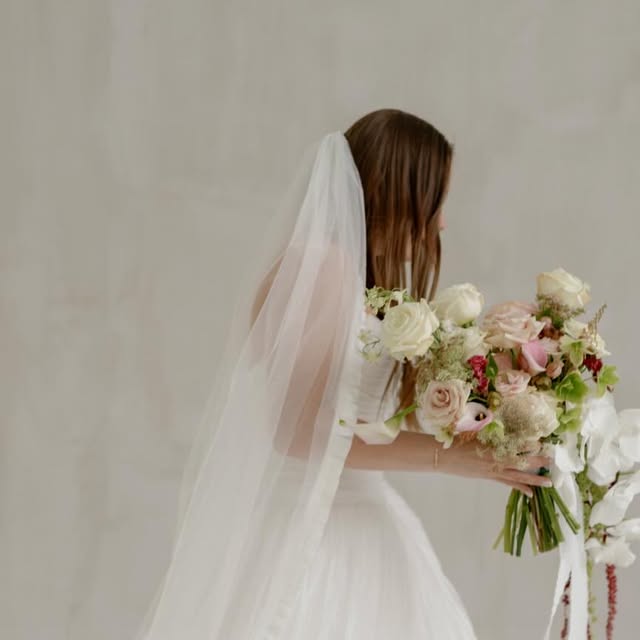 Bride in a veil holding a blush and cream rose bouquet